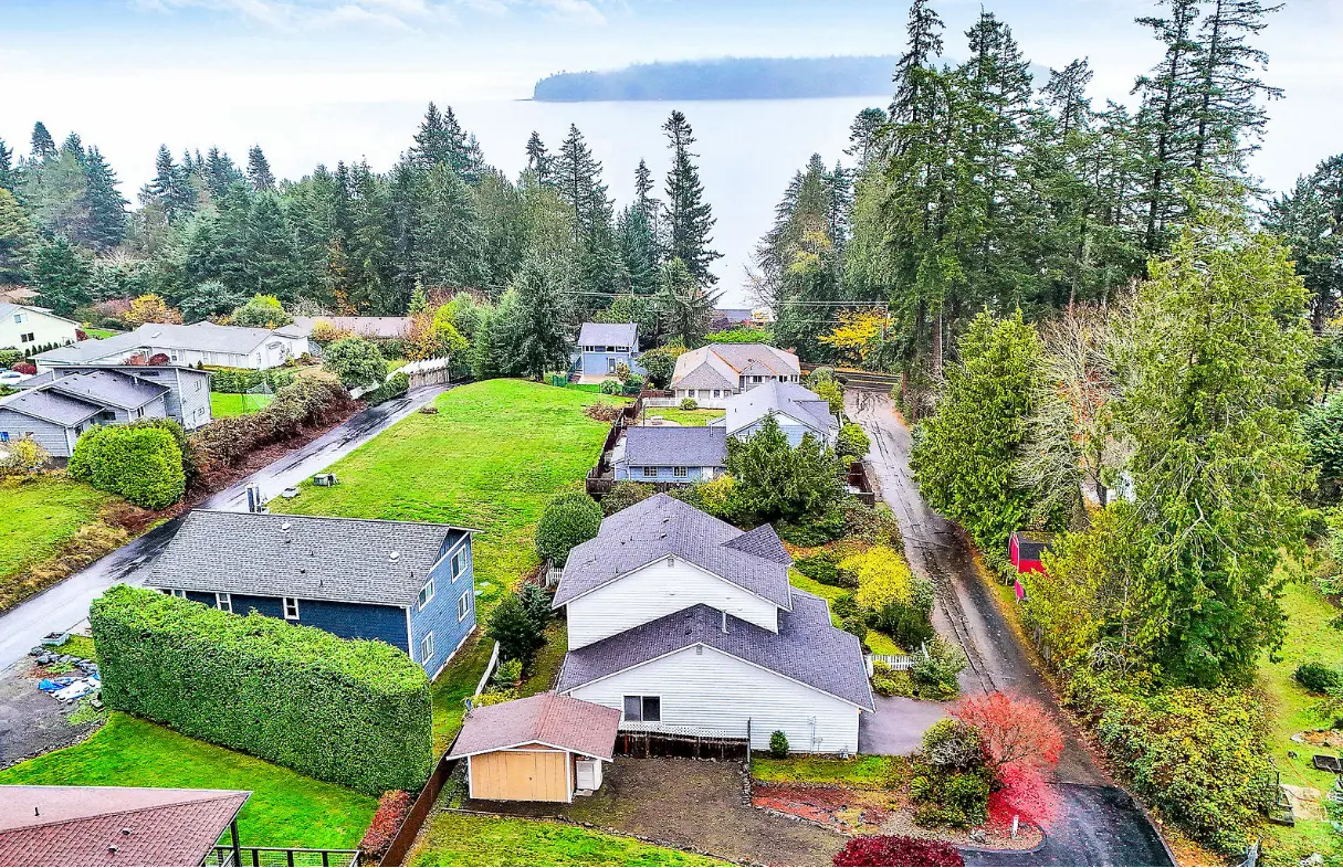 Aerial view of residential homes surrounded by trees and local roads